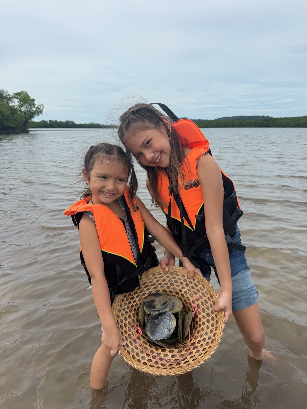 Two girls collecting shells at the mangrove lake