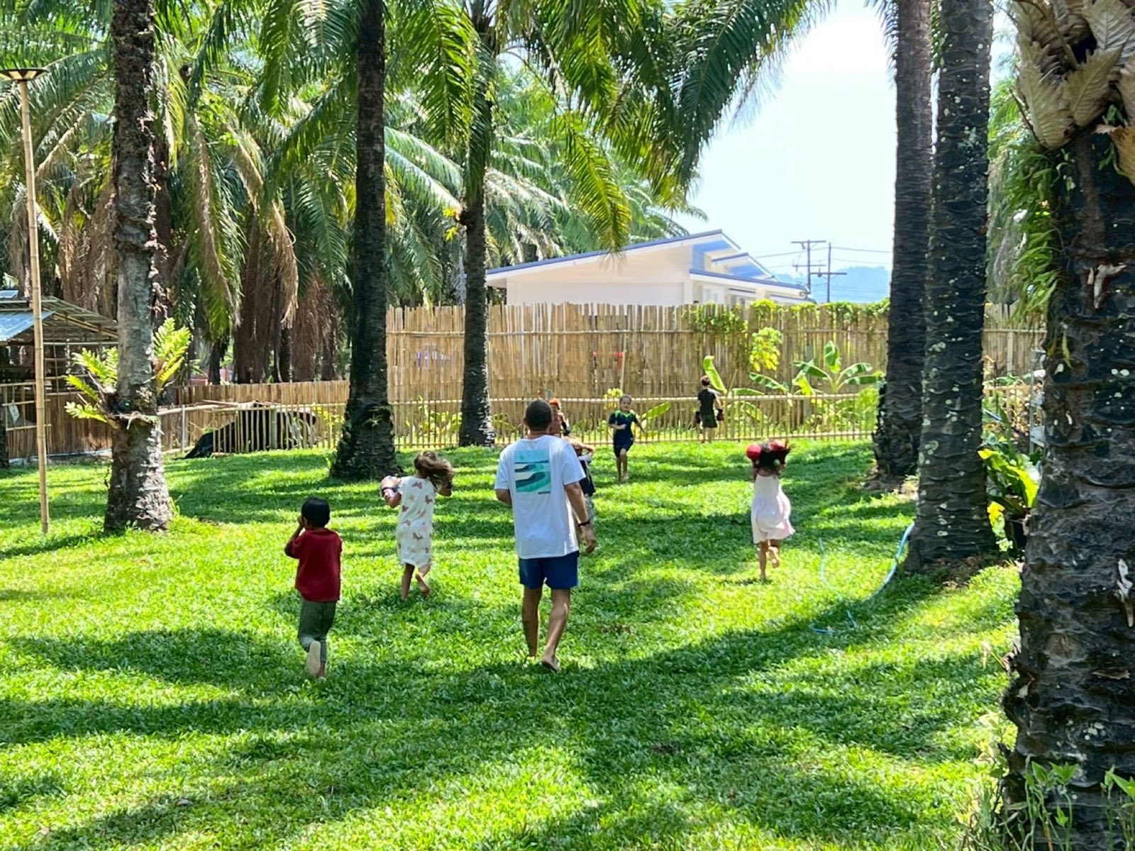 Children running freely through the palm grove at Bamboo Valley