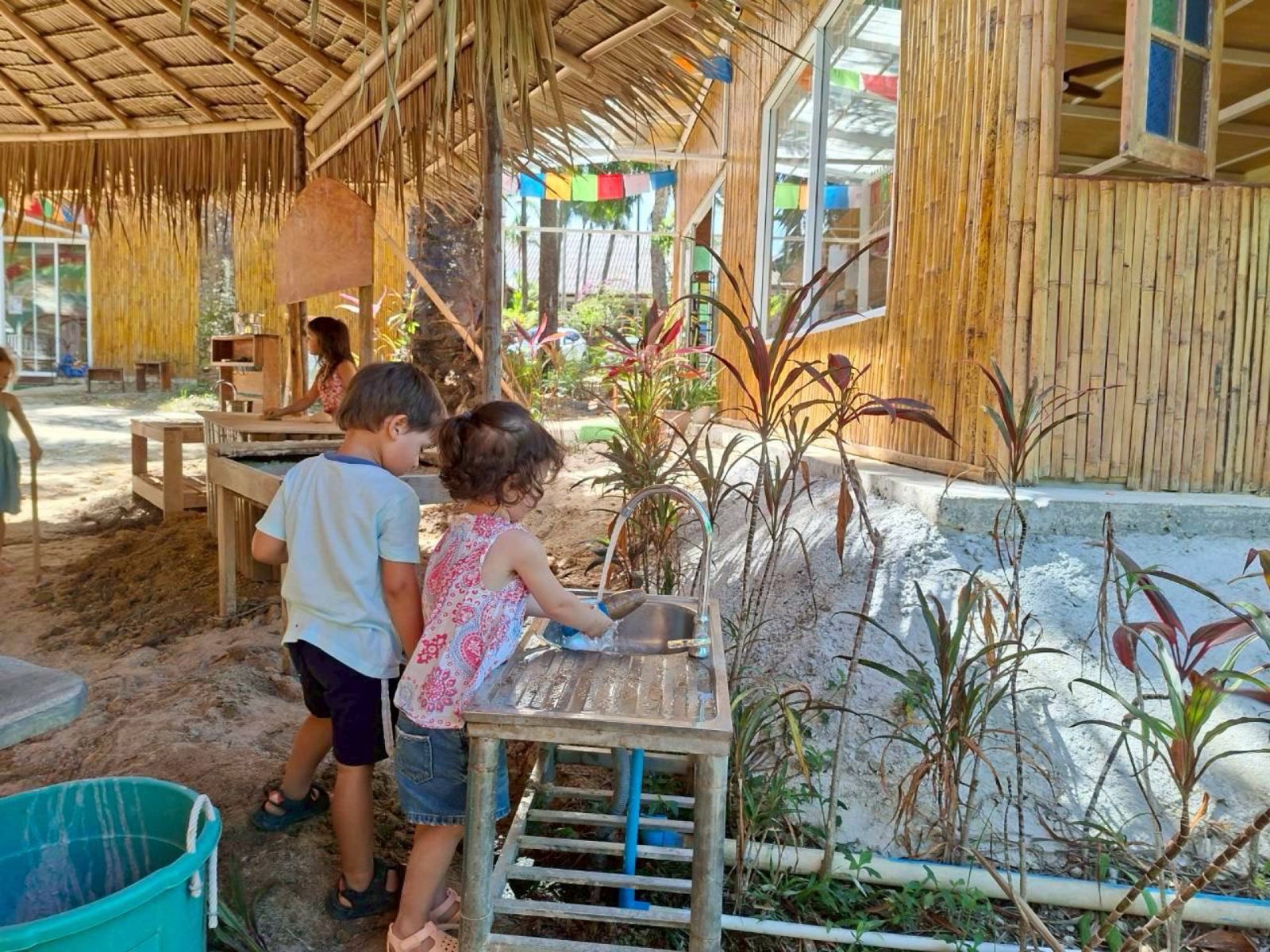 Children playing at the water station under the bamboo pavilion