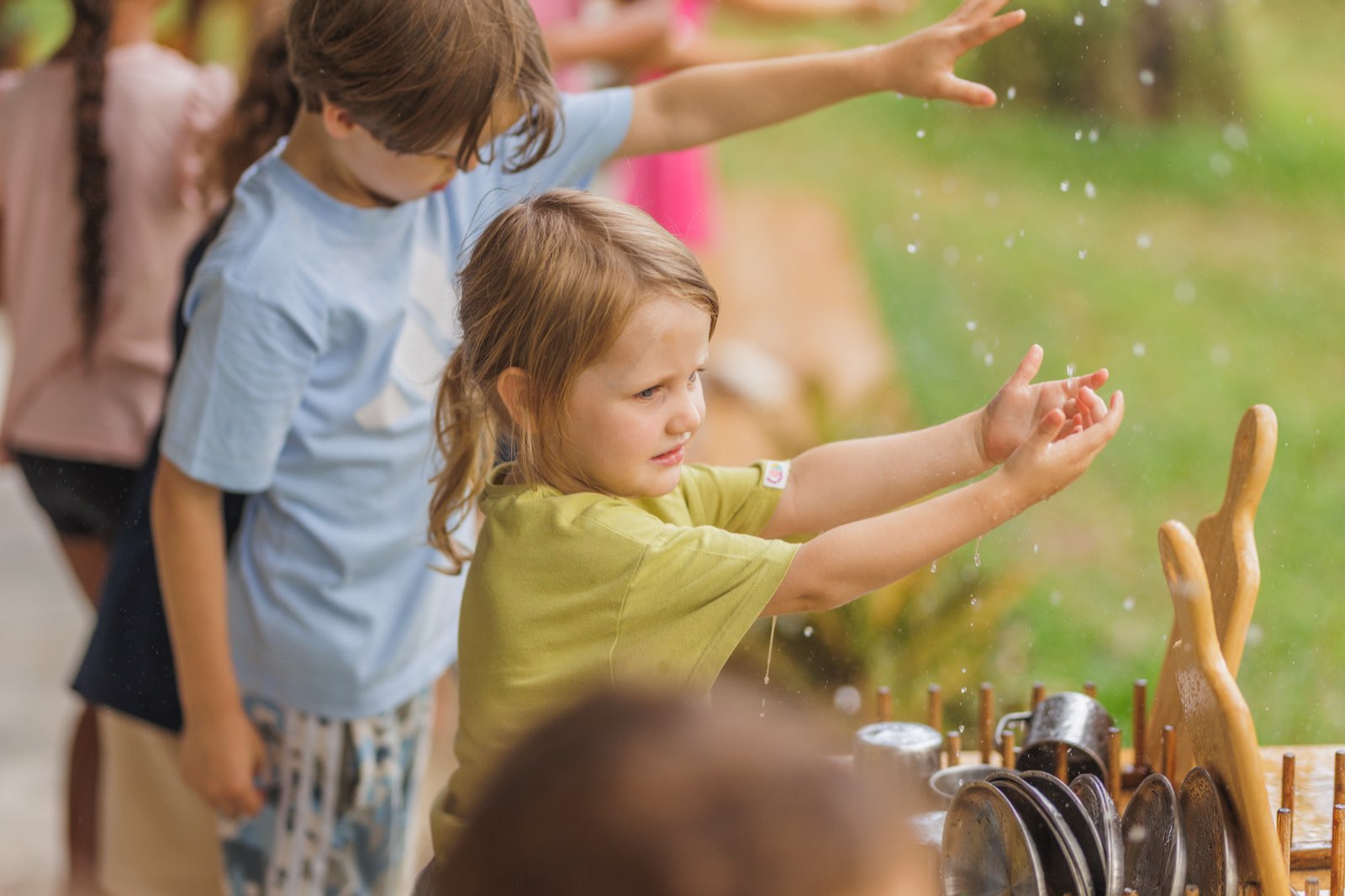 A girl absorbed in water play at the wooden mud kitchen